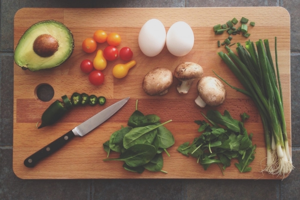 Überwiegend Gemüse und pflanzliche Lebensmittel dazu zwei Eier auf einem Schneidebrettchen