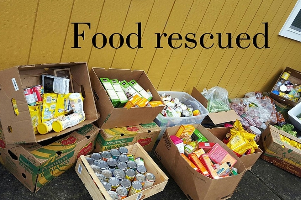 Zahlreiche Lebensmittel in Dosen und Pappkartons verpackt stehen vor einer gelben Holzwand