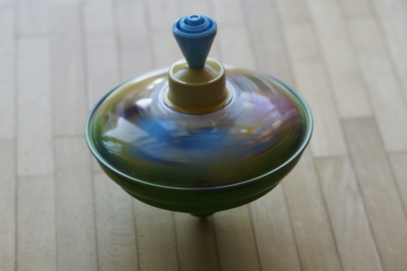 Ein sich in Bewegung befindender Spielzeugkreisel, der sich auf seiner Spitze dreht.