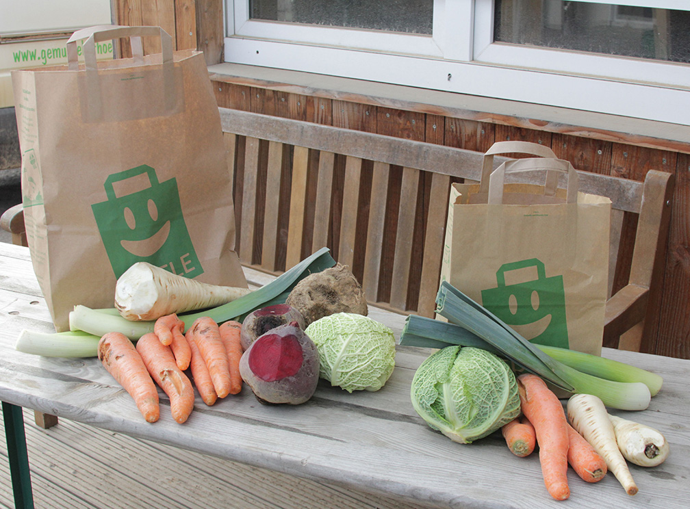 Gemüse vor bedruckten Papiertüten