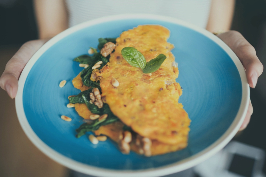 Hände halten Teller mit gefülltem Pfannkuchen