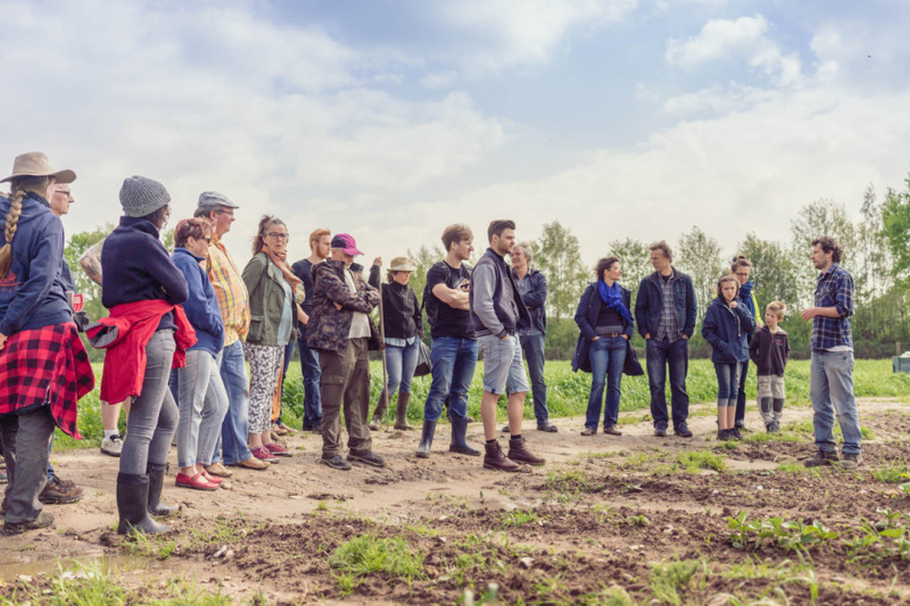 Menschen im Halbkreis auf einem Acker