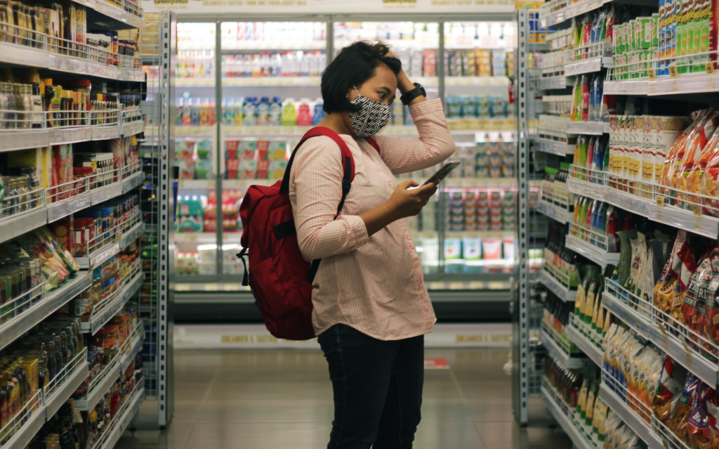 woman in grocery aisle looking at shelves confused