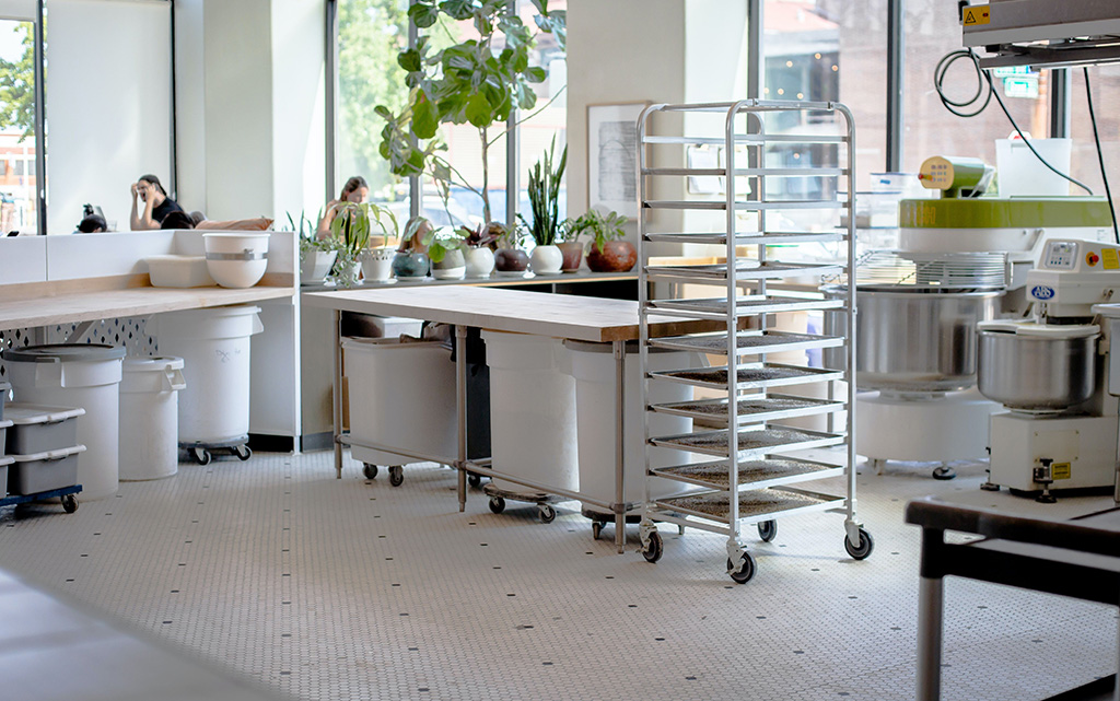 picture of a commercial kitchen with guest sitting at tables in the background